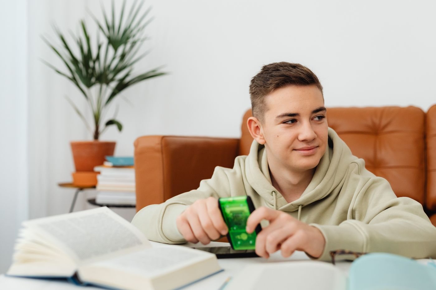 A teenage boy with a calculator beside an open book, studying at home